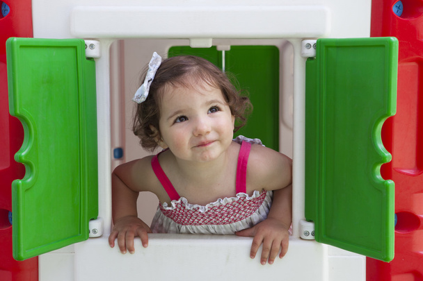 Ragazzina sorridente attraverso la finestra della casetta dei bambini
 - Foto, immagini