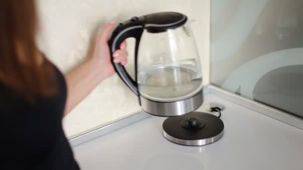 Beautiful woman turning on modern glass electric kettle on the fancy contemporary kitchen. - Footage, Video
