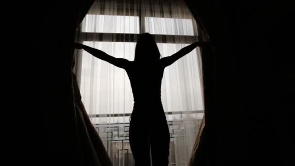 Vrouw door het raam en opening gordijnen, verhuur van natuurlijke licht komen alle hoeken van de kamer. - Video