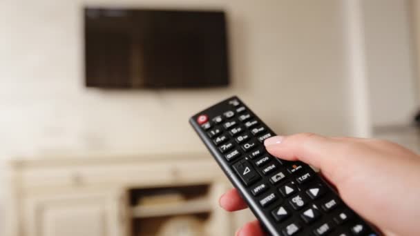 Hand holding TV remote control and changing channels on television. - Footage, Video