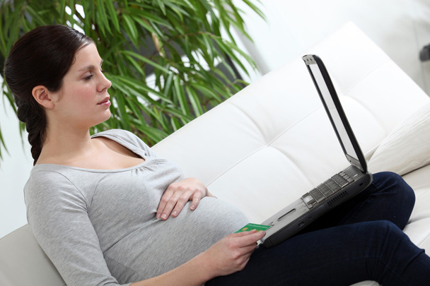 Pregnant woman sat on sofa - Foto, afbeelding