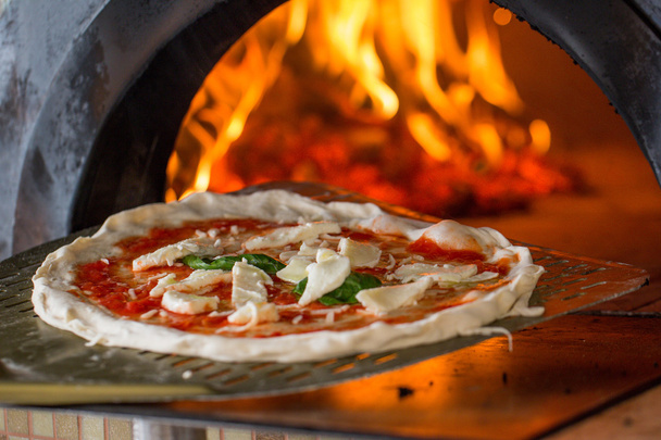 italian pizza getting in a wood burning pizza oven. - Photo, Image