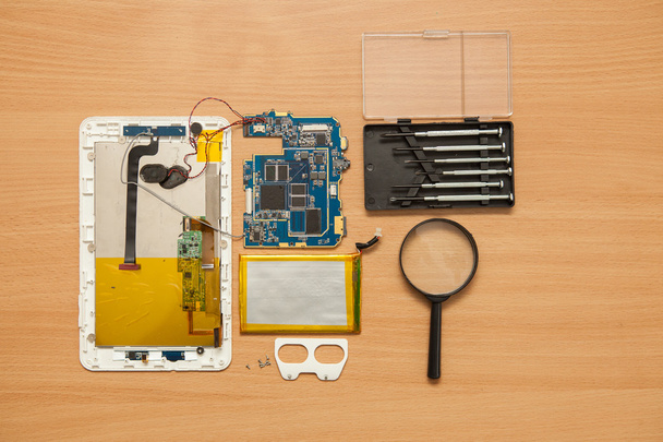 Disassembled tablet and tools on a wooden background. View from  - Foto, Imagen