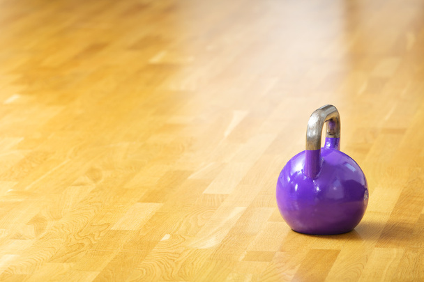 Jeden kettlebell stojí na podlaze na fitness tělocvičně - Fotografie, Obrázek