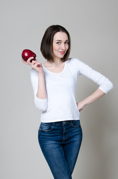 Happy slender woman holding apple isolated on a white background. Looking at camera - Φωτογραφία, εικόνα