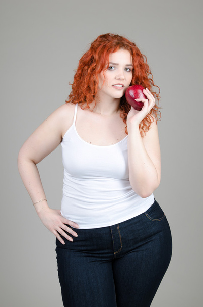 beautiful fat girl with red hair with apples in hands on grey background - Fotografie, Obrázek