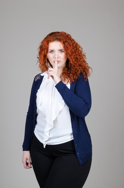 beautiful fat girl with red hair in a business suit on a gray background - Zdjęcie, obraz