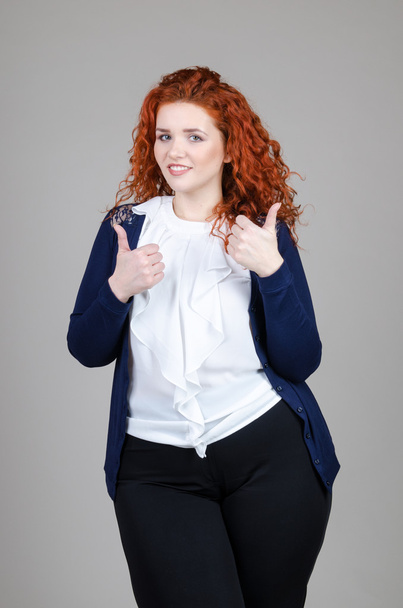 beautiful fat girl with red hair in a business suit on a gray background - Foto, immagini