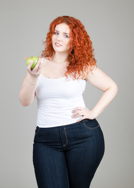 krásná tlustá dívka s červenými vlasy s jablky v rukou na šedém pozadí - Fotografie, Obrázek