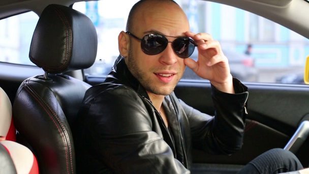 Kale man in zwarte jas en zonnebril autorijden - Video
