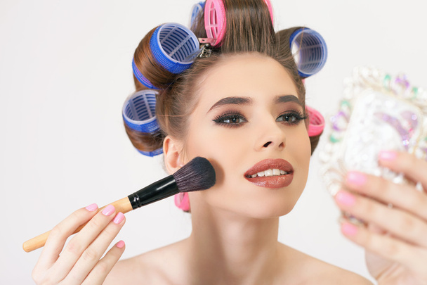 Young girl doing makeup and hairstyle using curlers - Fotó, kép