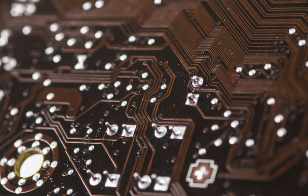 Macro closeup of a computer PCB Motherboard using brown and blac - 写真・画像
