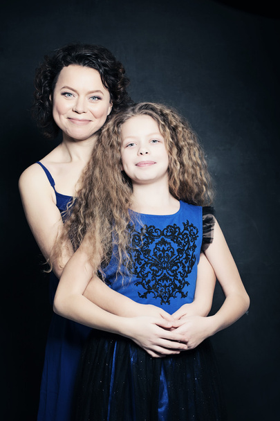 Beautiful Mother and Daughter Embracing on Blue Background - Фото, изображение