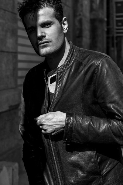 Handsome man portrait in the shadows wearing leather jacket - 写真・画像