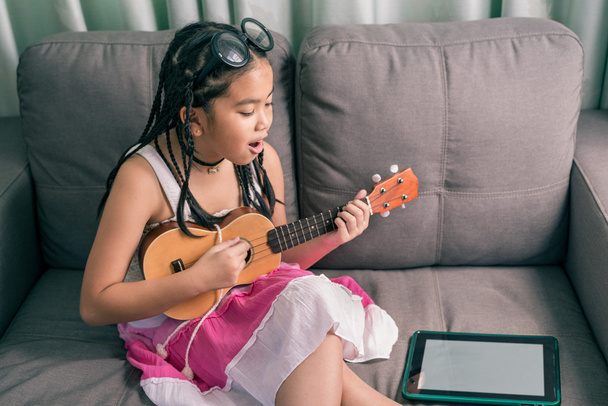Счастливая улыбающаяся девочка учится играть музыку
 - Фото, изображение