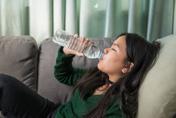 Kaunis nuori tyttö juo vettä sohvalla
  - Valokuva, kuva