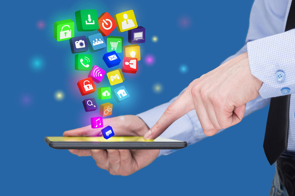 Empresário segurando um tablet pc com ícones de aplicativos móveis na tela virtual. Conceito de Internet e negócios
. - Foto, Imagem