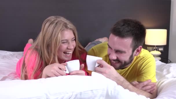 Smiling couple drinking coffee lying in the bed, closeup - Video, Çekim