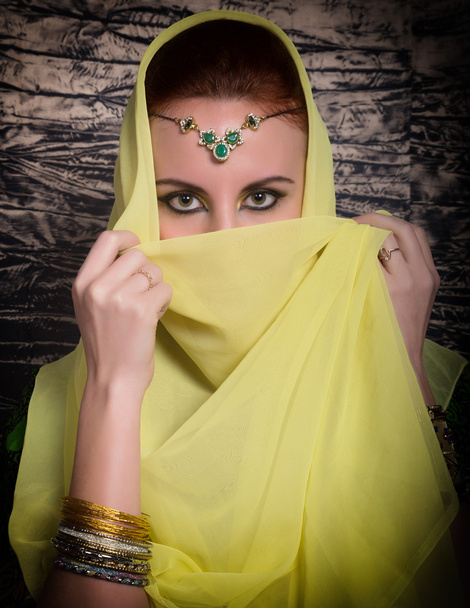 Closeup of beautiful young woman with oriental make-up and shawl over her head. caucasian woman dressed in oriental style - Foto, Imagem