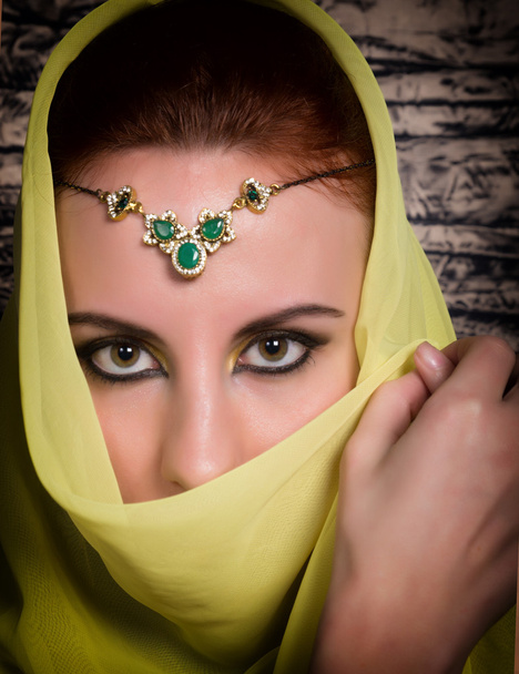 Closeup of beautiful young woman with oriental make-up and shawl over her head. caucasian woman dressed in oriental style. Professional makeup - Foto, imagen