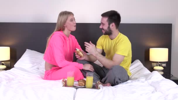 Couple snuggled under duvet eating breakfast - Filmati, video