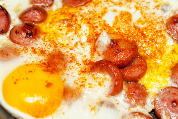 chicken eggs and hot sausages, sprinkled with red pepper - Foto, Bild