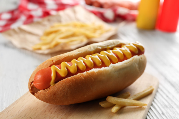 Hot dog with fried potatoes on craft paper - 写真・画像