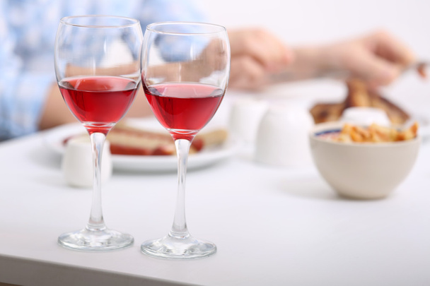 Dinner with glasses of wine on light blurred background - Foto, Imagen