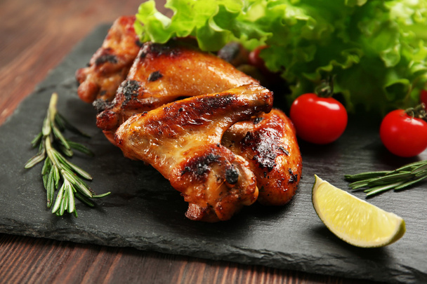 Baked chicken wings with vegetables on slate plate - Φωτογραφία, εικόνα