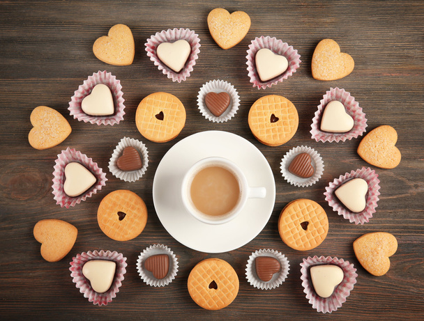Concepto Valentine. Composición de copa, galletas y caramelos sobre fondo azul
 - Foto, Imagen