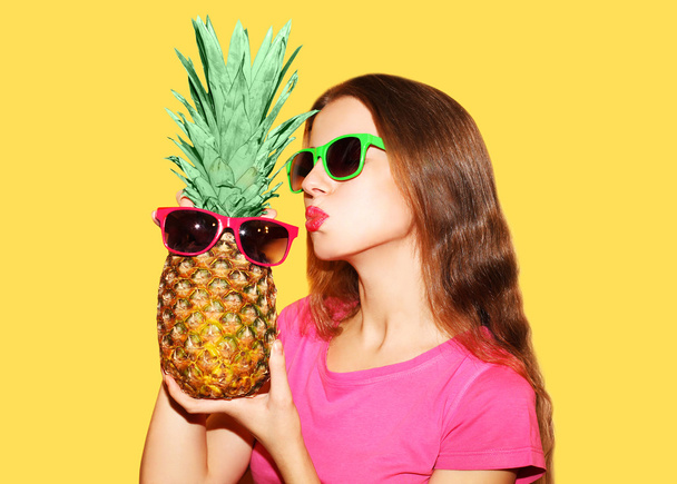 Fashion portrait pretty woman and pineapple in sunglasses over y - Fotó, kép