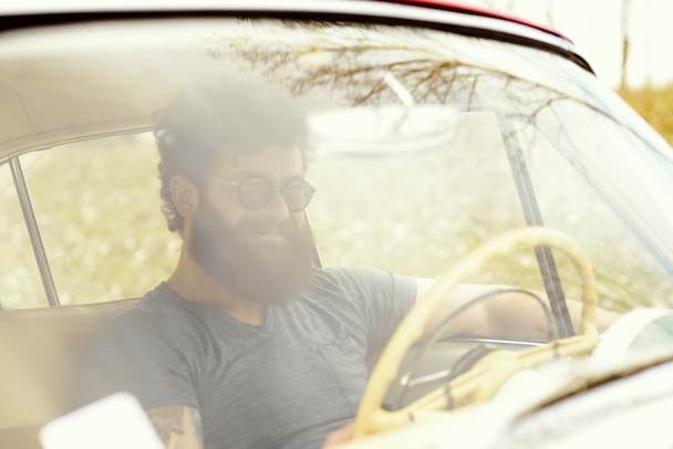 Bearded man playing guitar, near retro car - Photo, Image