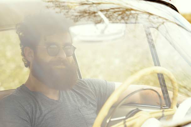 Bearded man playing guitar, near retro car - Photo, Image
