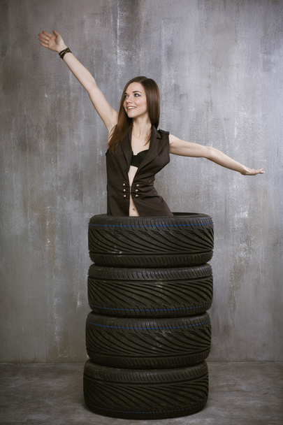 young girl stands inside tires, spread his hands, on a backgroun - Foto, Imagen
