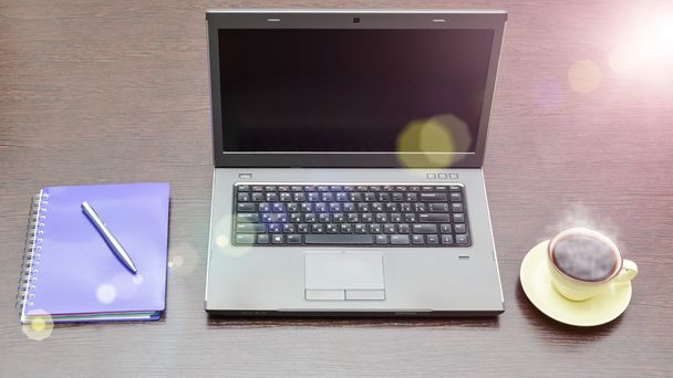 Laptop, Adressbuch, Tasse und Stift auf dem Tisch. Sonneneruption - Foto, Bild