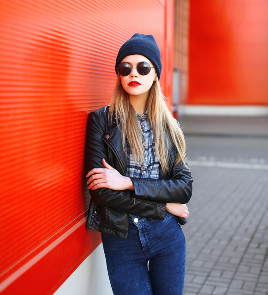 Fashion young woman in rock black style over red background - 写真・画像