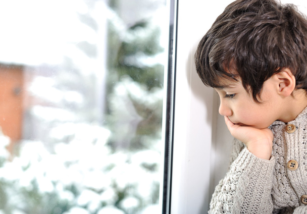 Sad kid on window cannot go out because of cold and snow - Φωτογραφία, εικόνα