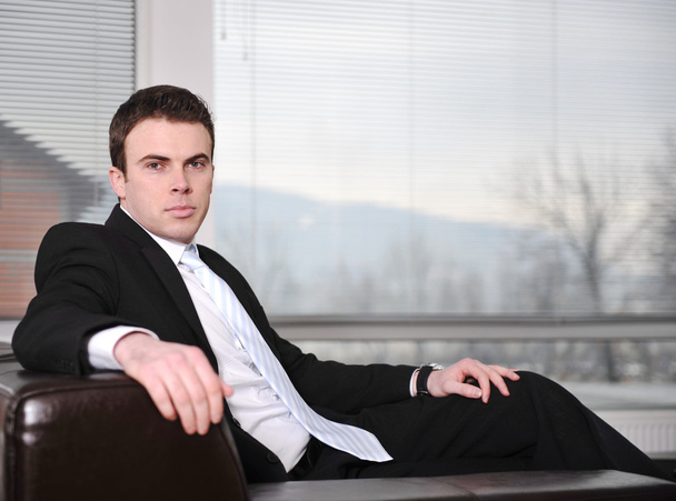 Businessman sitting on leather sofa in office - Foto, imagen