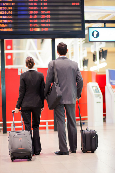 Business travellers looking at airport information board - Φωτογραφία, εικόνα