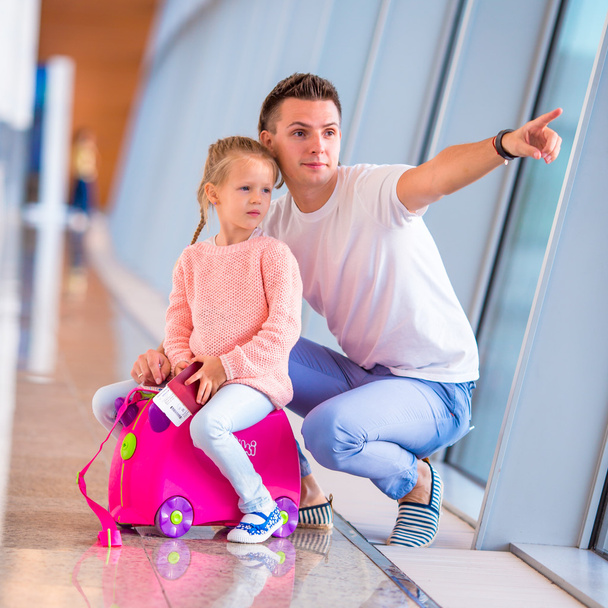 Onnellinen perhe matkatavaroiden ja tarkastuskortin kanssa lentokentällä odottamassa lennolle pääsyä
 - Valokuva, kuva