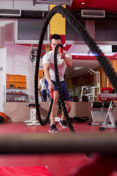 Young man working out with battle ropes at a gym - Zdjęcie, obraz