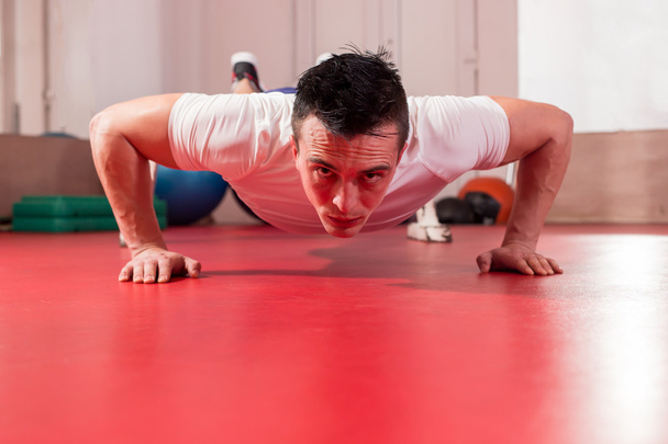 A muscular man doing a pushups at the crossfit gym - Фото, зображення