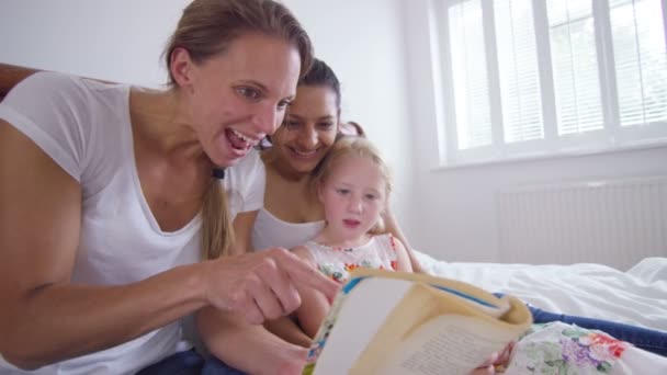 gay female couple reading with daughter - Záběry, video