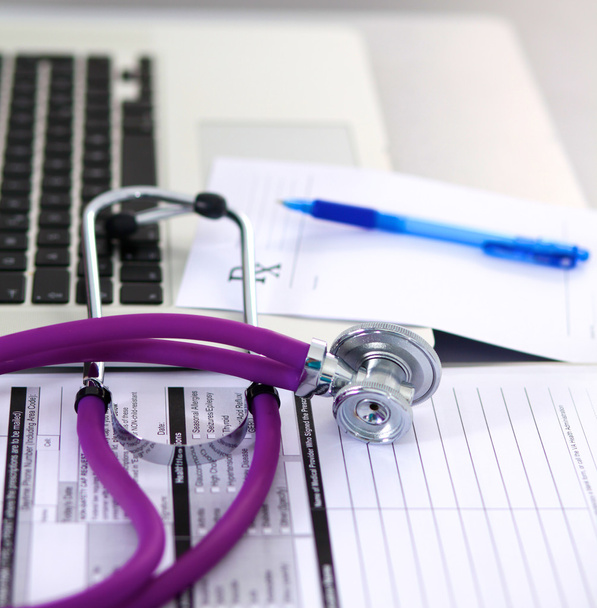 egy orvosi sztetoszkóppal közelében egy laptop, egy fából készült asztal, fehér - Fotó, kép