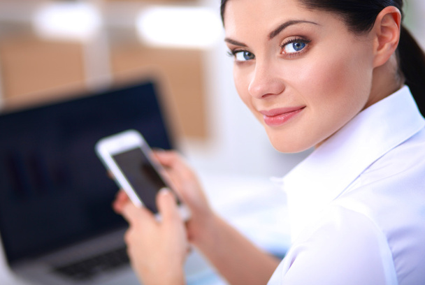 Businesswoman sending message with smartphone sitting in the office - Фото, зображення