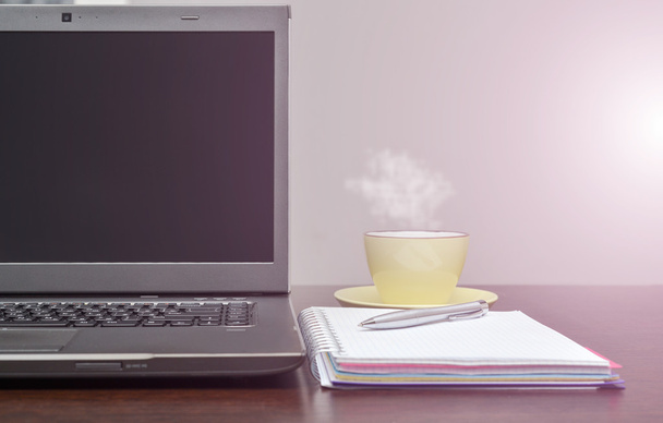 Laptop een adresboek, cup en pen op tafel. zon flare - Foto, afbeelding