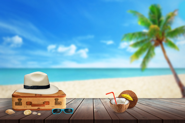 Hat utas bőrönd, napszemüveg, kókusz, shell beach asztalra. Szabad hely, a szöveg. Strand, tenger, tenyér és a kék ég, a háttérben. - Fotó, kép