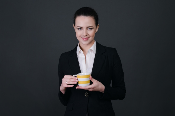 Portrait of smiling  business woman, on black background with coffee cup. - Valokuva, kuva