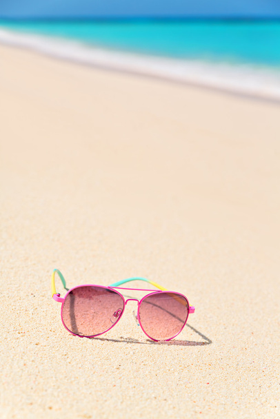 Óculos de sol rosa na praia, composição vertical
 - Foto, Imagem