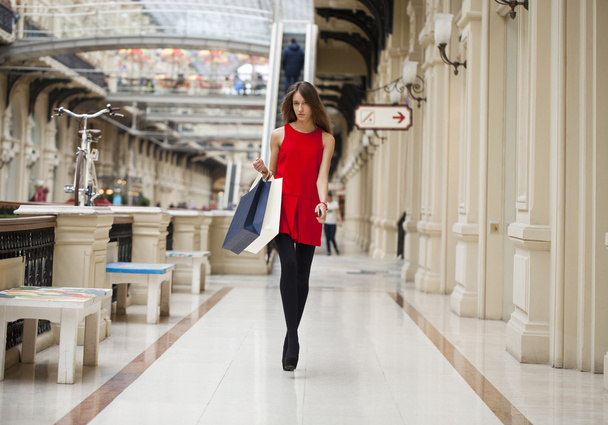 Young woman in red dress walking in the shop  - Fotoğraf, Görsel